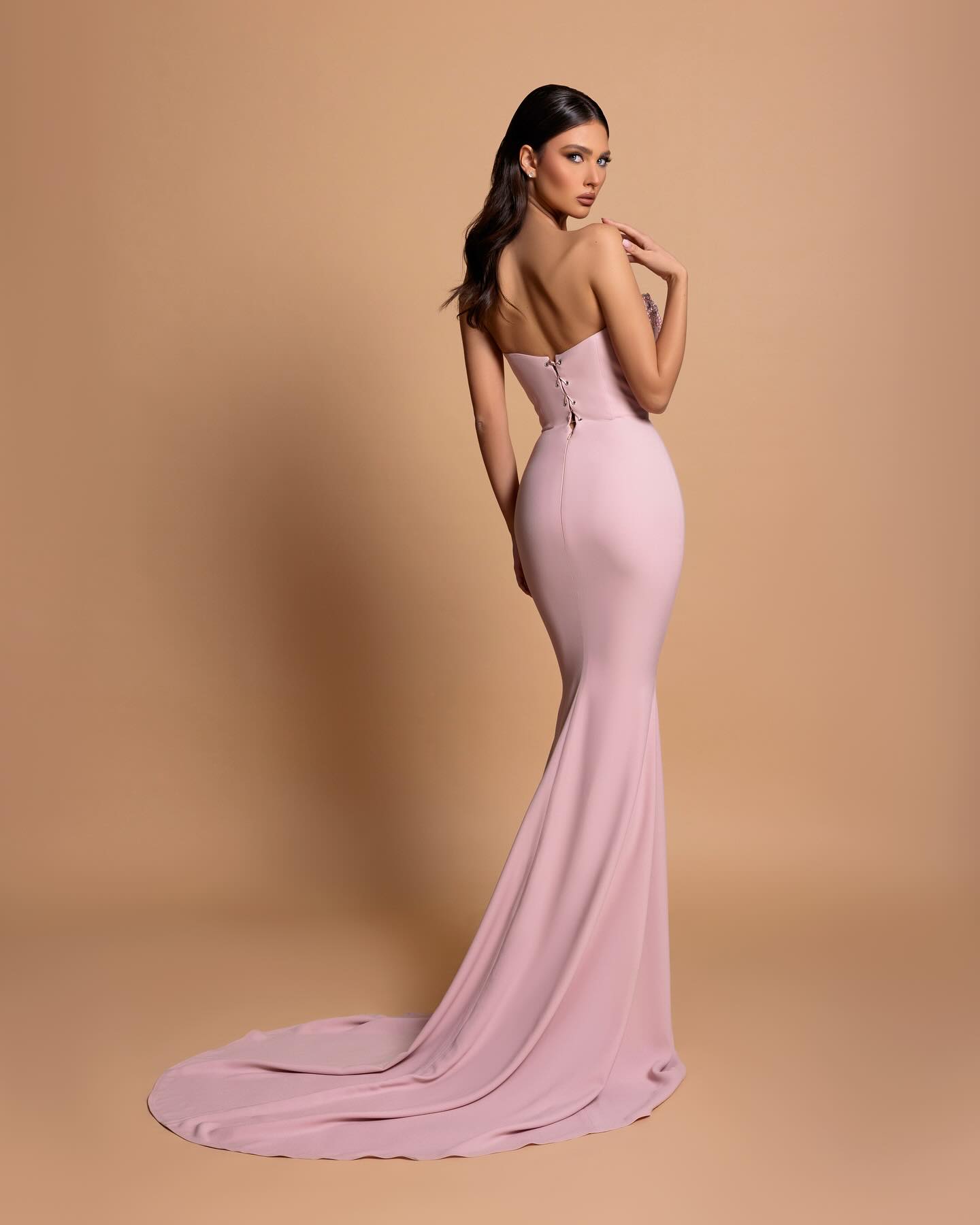 Impresionante vestido de fiesta rosa con escote en V, sin tirantes, sin mangas, de satén con pedrería y espalda abierta y cola.