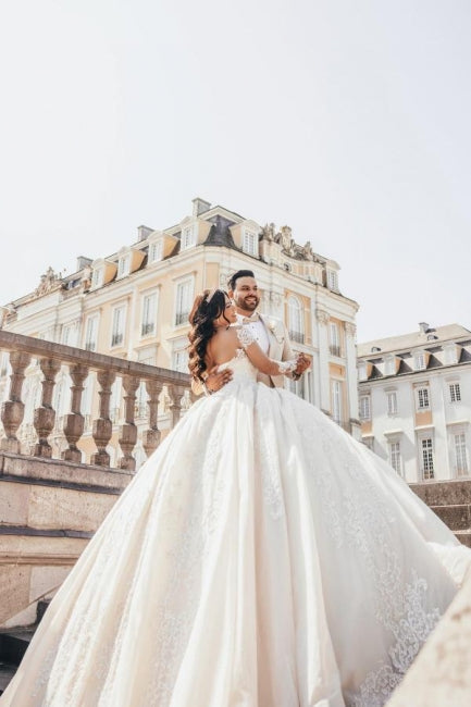 Vestido de novia de tul con escote corazón, mangas largas, apliques y cuentas, largo hasta el suelo.