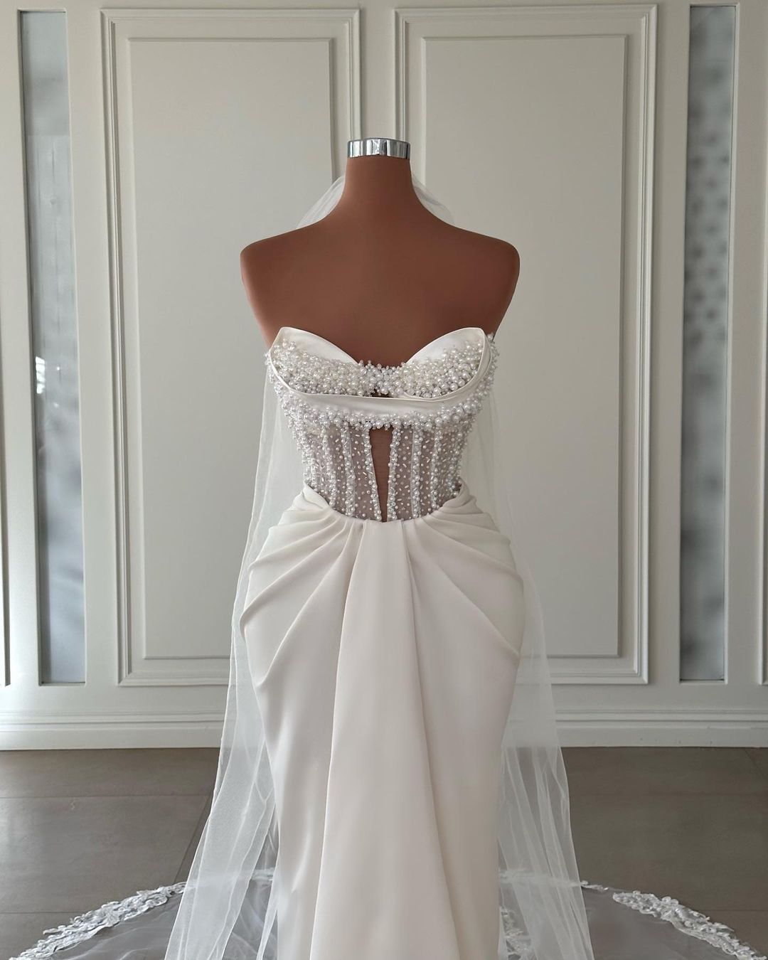 Vestido de novia largo de satén color marfil con escote sirena, sin mangas y perlas
