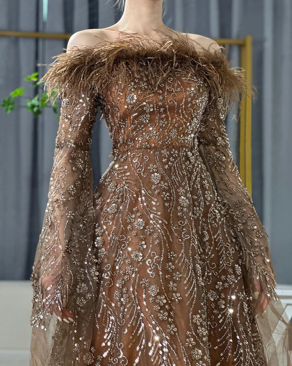 Vestido de noche marrón con plumas y hombros descubiertos y mangas estilo capa LA72401