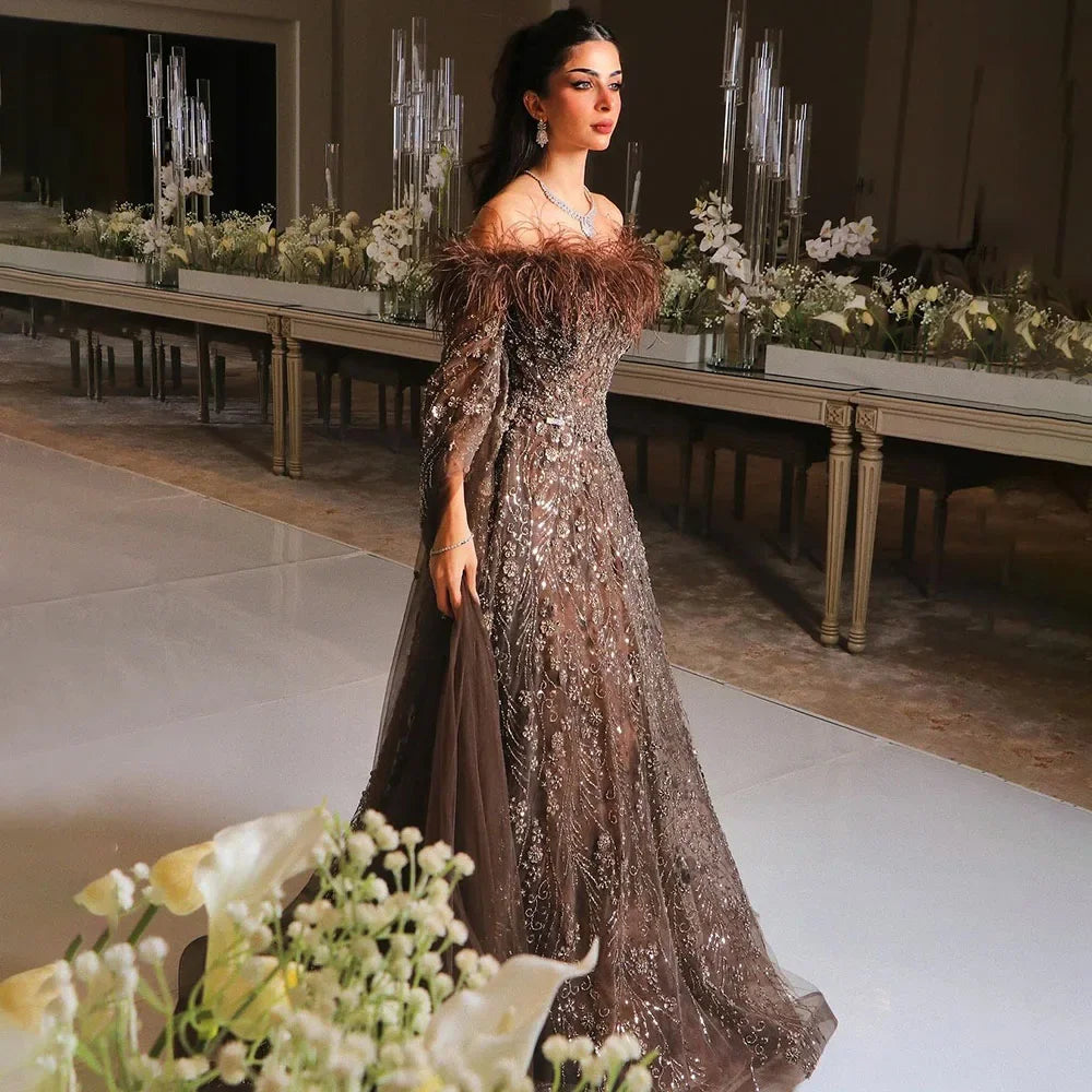Vestido de noche marrón con plumas y hombros descubiertos y mangas estilo capa LA72401