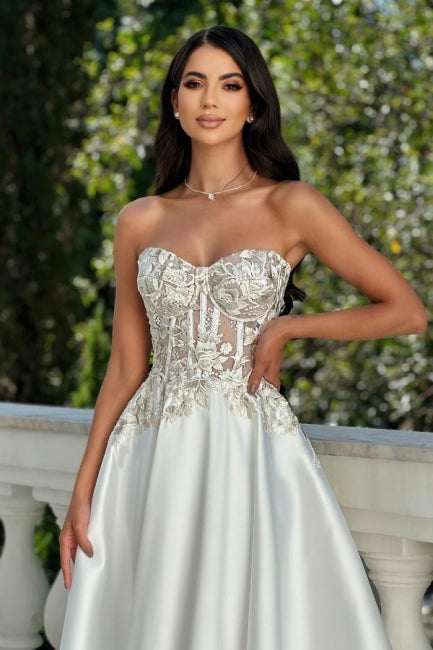 Impresionante vestido de fiesta color marfil sin mangas con escote corazón, encaje satinado y apliques.
