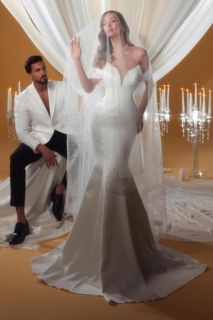 Encantador vestido de novia color marfil sin mangas, con hombros descubiertos y escote en forma de columna y cuentas.