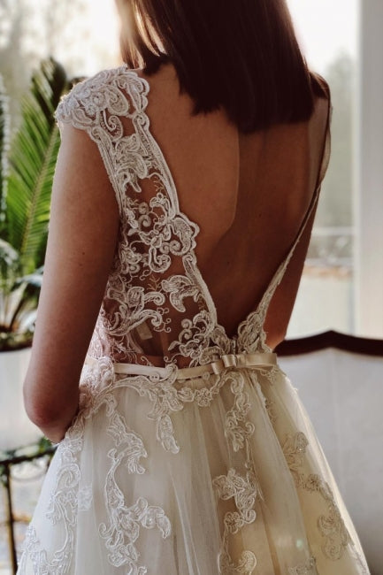 Vestido de novia de encaje color marfil, corte A, largo hasta el suelo, escote en V y jardín.