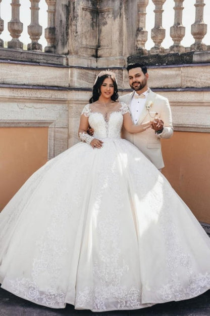 Vestido de novia de tul con escote corazón, mangas largas, apliques y cuentas, largo hasta el suelo.