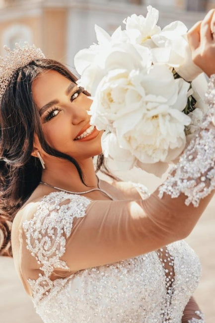 Vestido de novia de tul con escote corazón, mangas largas, apliques y cuentas, largo hasta el suelo.