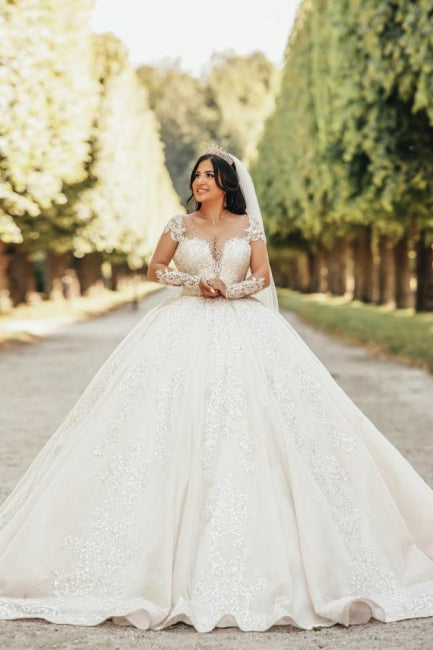 Vestido de novia de tul con escote corazón, mangas largas, apliques y cuentas, largo hasta el suelo.