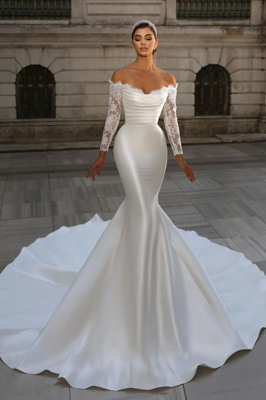 Vestido de novia largo blanco con escote sirena, mangas largas y cola desmontable.