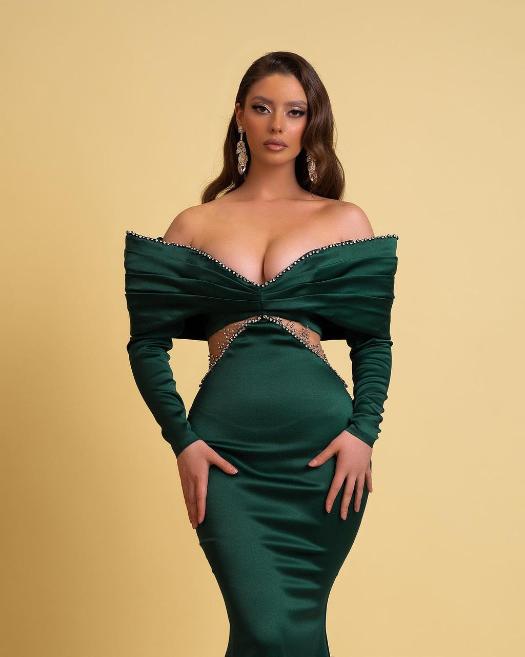 Vestido de fiesta largo de diseño verde oscuro con escote sirena, hombros descubiertos, pedrería y mangas largas