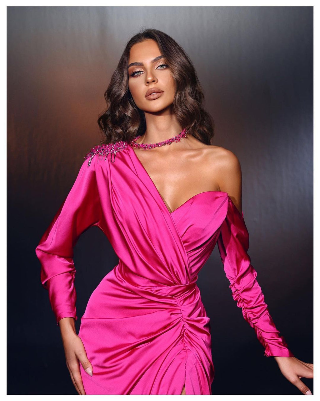 Vestido de fiesta largo fucsia de diseñador con un solo hombro, mangas largas y cuentas, con abertura