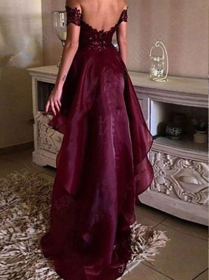 Elegante vestido de fiesta de organza con apliques asimétricos, sin mangas y hombros descubiertos.