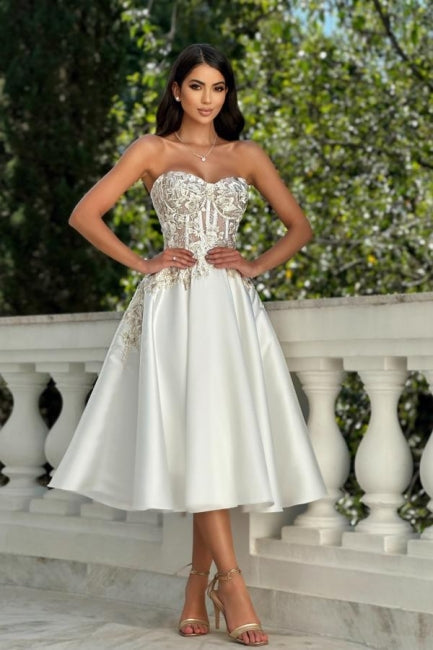 Impresionante vestido de fiesta color marfil sin mangas con escote corazón, encaje satinado y apliques.