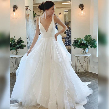 Wunderschönes ärmelloses Tüll-Brautkleid mit tiefem V-Ausschnitt und Rüschen