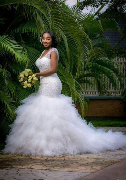 Hermoso vestido de novia de sirena con escote en V, sin mangas y con cuentas.