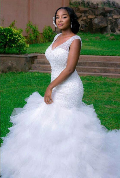 Hermoso vestido de novia de sirena con escote en V, sin mangas y con cuentas.