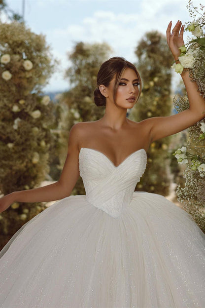 Vestido de novia encantador de corte A con escote en V, sin mangas y brillo, con cola