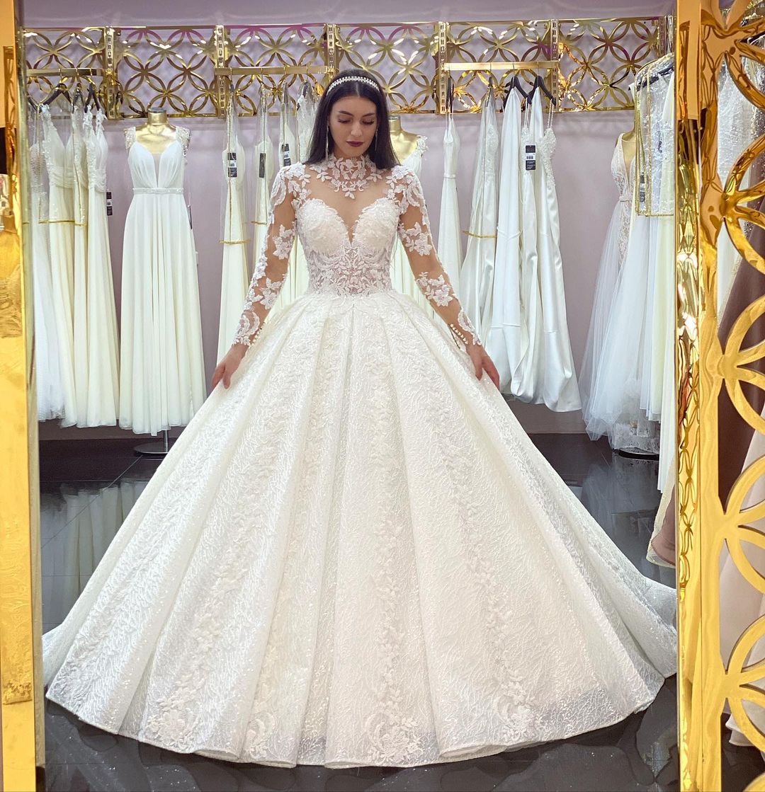 Wunderschönes langes Prinzessinnen-Brautkleid mit hohem Halsausschnitt, Spitzenapplikationen und Ärmeln