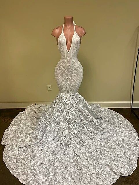Hermoso vestido de fiesta blanco con escote en V y sin mangas, corte sirena, con encaje y flores en la parte inferior.