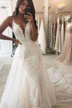 Vestido de novia estilo sirena con escote en V y tirantes finos y cola desmontable.