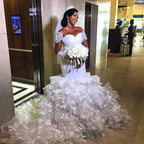 Vestido de novia sirena con mangas cortas, hombros descubiertos y cola con volantes