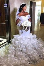Vestido de novia sirena con mangas cortas, hombros descubiertos y cola con volantes